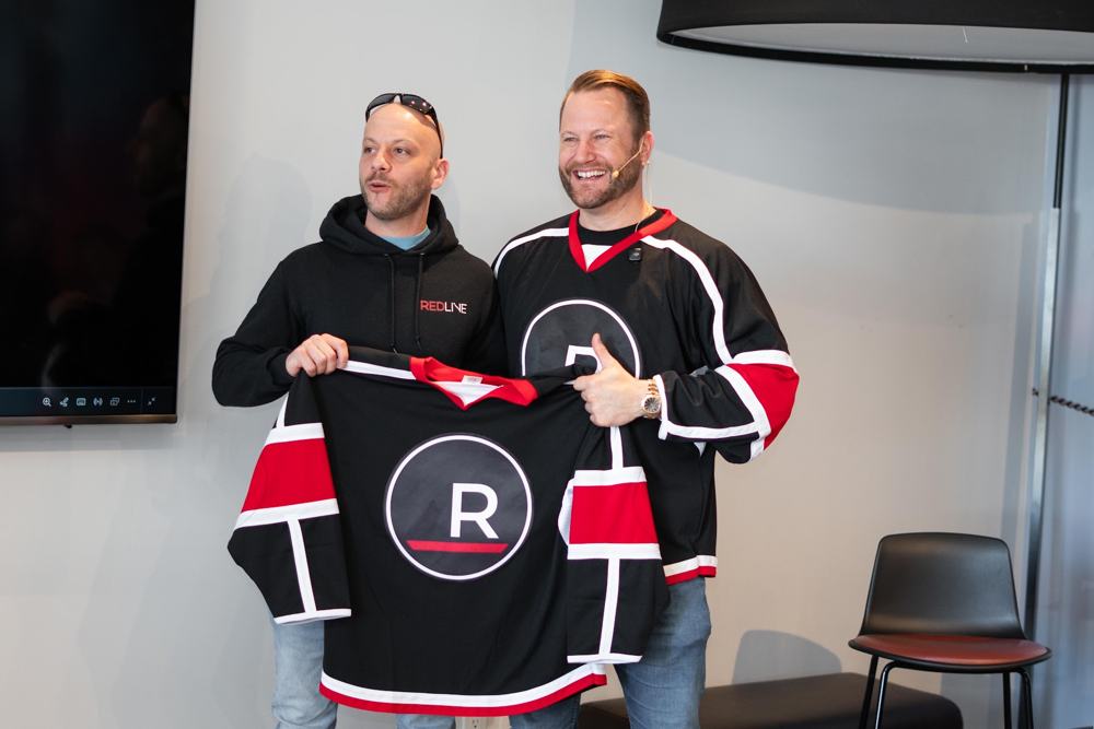 Two agents holding up a Redline jersey
